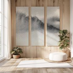 an empty room with three paintings on the wall and a potted plant next to it