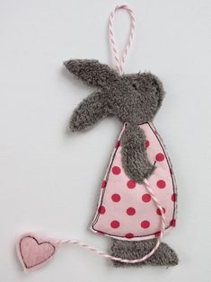 a gray stuffed animal hanging from a pink and white polka dot dress on a string