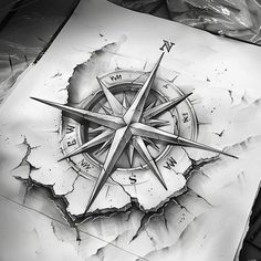 a black and white drawing of a compass on paper with other items around the image