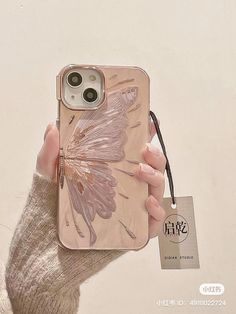 a person holding up a phone case with a butterfly on it's back,