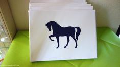 a white bag with a black silhouette of a horse on it sitting on top of a green table