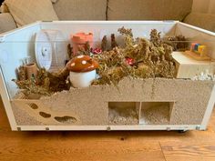 a toy house filled with lots of toys on top of a wooden floor next to a couch