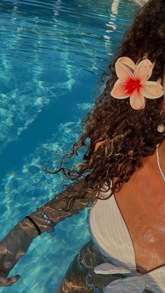 a woman in a white top is floating in the water with a flower on her head