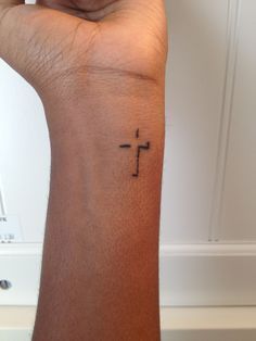 a woman's arm with a small cross tattoo on the left side of her wrist