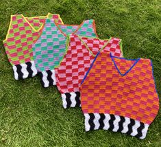 four knitted bags sitting on top of the grass in front of some green grass