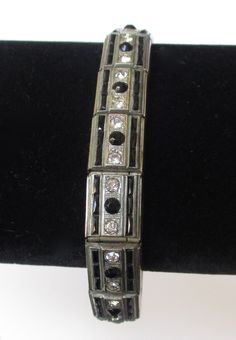 "Art-Deco Rhodium Plated Silver Tone Bracelet With Black and Clear Paste Stones Circa. 1920-1925 American Rhodium plated silver tone bracelet Clear and black faceted round paste stones French cut baquettes which are very difficult to find. This bracelet screams \"deco!\" Marked ALLCO on back of catch Original catch works perfectly Rhodium plating protects the piece from tarnishing Rhodium plating is a costly process, so only the finer pieces have this used Measures 7 inches long slightly less th Silver Jeweled Bracelets Costume Jewelry, Silver Jeweled Costume Bracelets, Silver Jeweled Bracelet For Formal Occasions, Silver Jeweled Costume Jewelry Bracelets, Adjustable Art Deco Jewelry Bracelet, Formal Silver Jeweled Bracelet, Silver Costume Jewelry Bracelets For Evening, Silver Costume Jewelry Bracelet For Evening, Art Deco Silver Jubilee Bracelet