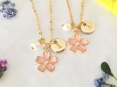 three personalized necklaces with flowers and pearls are shown on a white tablecloth