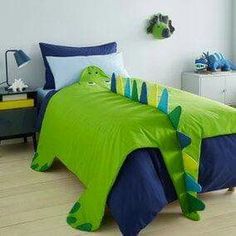 a child's bed with a green and blue dinosaur comforter on the bottom