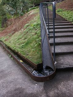 a set of stairs with grass growing on the side and water running down them from above