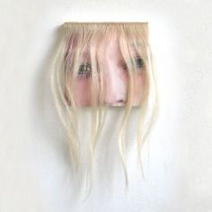 a woman's head with long blonde hair hanging on the wall above her head