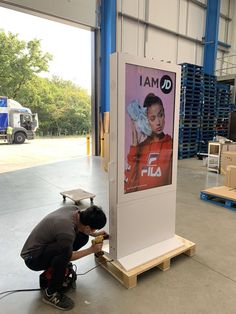 a man kneeling down next to a sign with a poster on it's side