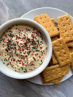 crackers and dip in a bowl on a plate with sprinkles next to it