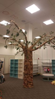 a fake tree in the middle of a room with lots of bookshelves and shelves