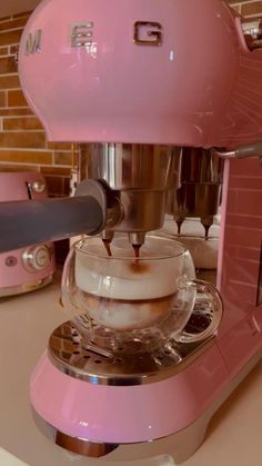 a pink coffee maker is being filled with liquid