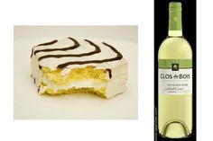 a bottle of wine next to a piece of cake with chocolate icing on it