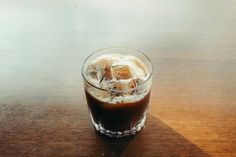 a glass filled with ice sitting on top of a wooden table