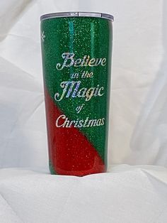 a green and red tumbler with believe in the magic of christmas written on it