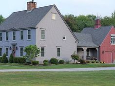 two large gray houses next to each other on a lush green field with trees in the background