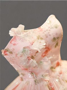 a pink and white dress with flowers on the skirt is shown in front of a gray background