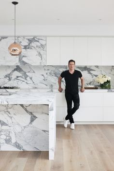 a man standing in front of a marble counter top next to a white kitchen island