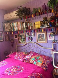 a bedroom with purple walls and lots of books on the shelves above the bed,