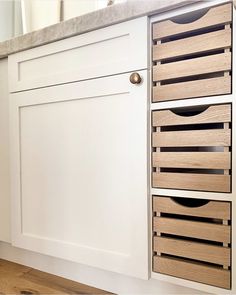 a kitchen with white cabinets and wooden drawers