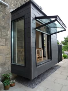 a small black building sitting on the side of a road next to a brick wall