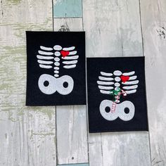 two black patches with white and red designs on them, one has a christmas decoration in the shape of a skeleton