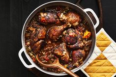 a pot filled with meat and vegetables on top of a table next to a wooden spoon