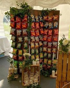 there are many bags of food on display in this tented area with flowers and greenery