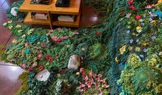 a living room filled with lots of green plants and flowers next to a wooden table