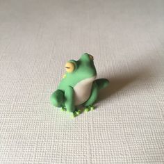 a small toy frog sitting on top of a white surface