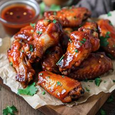 chicken wings covered in sauce and garnished with parsley on a cutting board