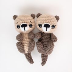 two crocheted teddy bears sitting next to each other on top of a white surface