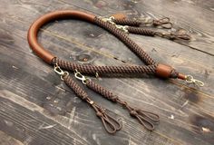 a brown leather leash with brass hardware on a wooden surface