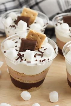 three dessert cups with marshmallows and chocolate on top are sitting on a table