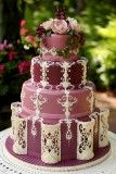 a three tiered wedding cake with pink flowers on top and white lace around the edges