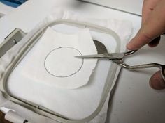 someone is cutting fabric with scissors on top of a piece of white material that has been sewn