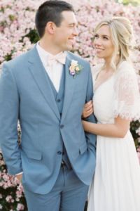 a bride and groom standing in front of pink flowers