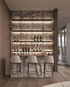 a bar with three stools in front of it and several bottles on the wall