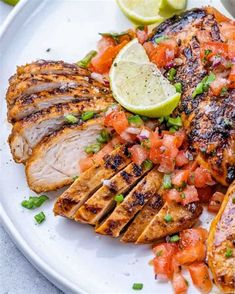 grilled chicken with tomatoes, onions and limes on a white plate