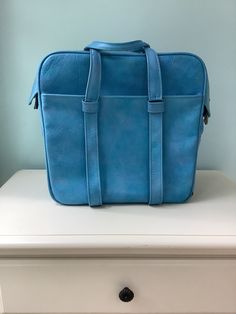 "Vintage Blue Vinyl \"Samsonite\" Carry On Luggage ~  1970's / 80's Baggage Double strap open top zippers with lock snap 2 Large exterior pockets with one that zips  Light blue vinyl lined interior with one pocket zips 4 Stainless steel feet ,roomy interior  Length -14 1/2\" Height -14 1/2\" Width - 7\" Handle drop - 6 1/2\" Weight -3 Lb 1 oz. View wear at edges,spot stain,wrinkled interior liner, and bottom pipping Sold as is , with lots of travel left in her !" Vintage Everyday Backpack Shoulder Bag, Vintage Shoulder Bag Standard Backpack For Everyday, Vintage Everyday Shoulder Bag Backpack, Retro Standard Backpack, Vintage Blue Bag With Large Capacity, Retro Style Standard Backpack, Vintage Rectangular Satchel For On-the-go, Vintage Blue Bags With Large Capacity, Retro Bags With Luggage Sleeve For Daily Use