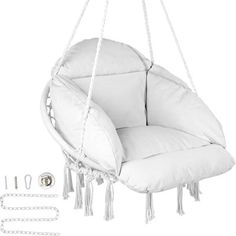 a white hanging chair with tassels and chains on the bottom, next to it's contents