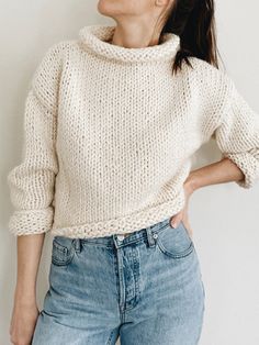 a woman standing in front of a white wall with her hands on her hips and looking up