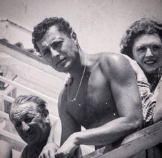 an old black and white photo of two people on a boat with one man holding something in his hand