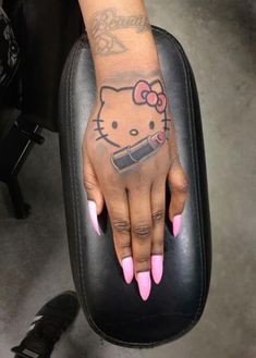 a hello kitty tattoo on the hand of a woman with pink nails and nail polish