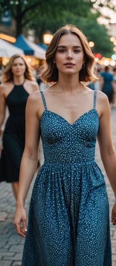 a woman in a blue dress is walking down the street with other people behind her