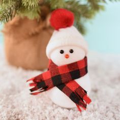 a small white snowman wearing a red and black scarf