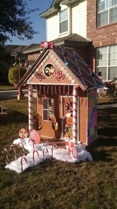 a gingerbread house with candy canes and candies on the lawn in front of it