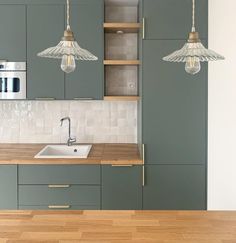 an image of a kitchen setting with green cabinets and white tile backsplashes